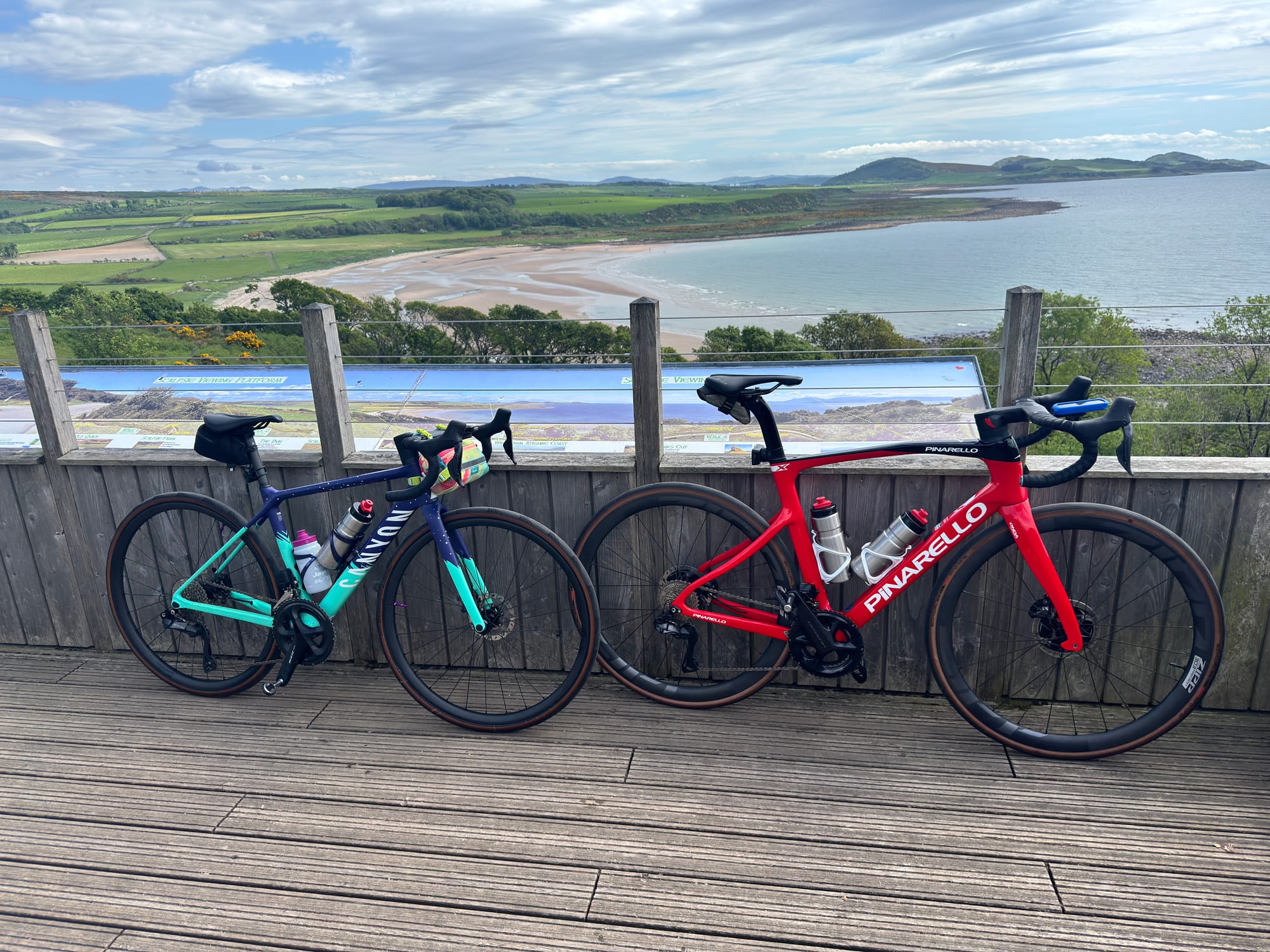 Two bicycles against a wooden wall, the sea and hills visible behind them.